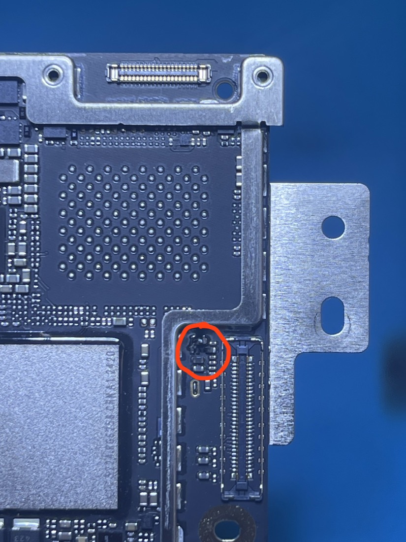 MacBook Air M2 A2681 logic board before repair: a spontaneously exploded capacitor fried three caps and blasted a hole into the board on the power line to the daughter-board FPC connector, causing no power