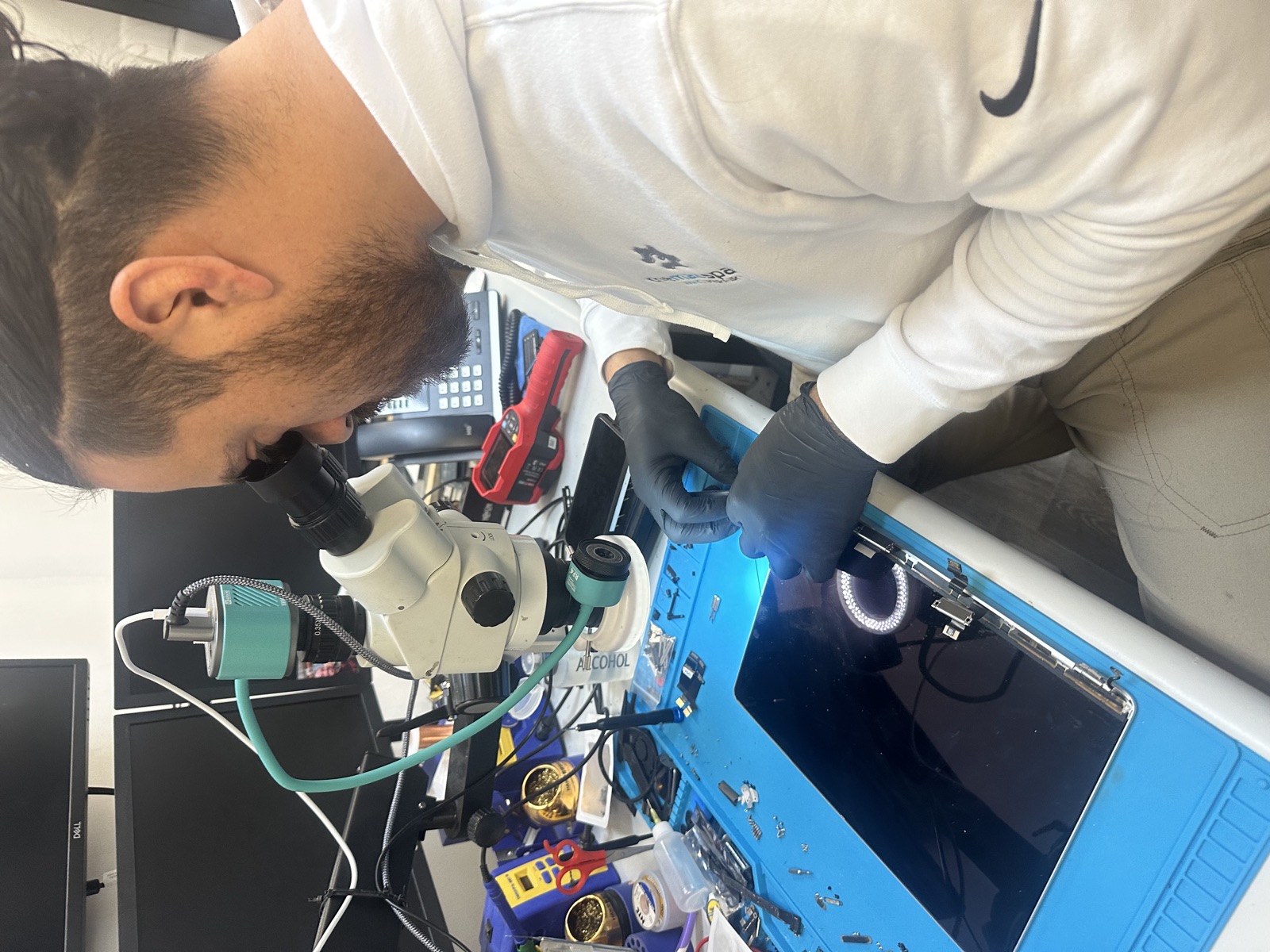 Technician at The Mac Space using stereo microscope for precision MacBook LCD panel repair in Marietta, GA